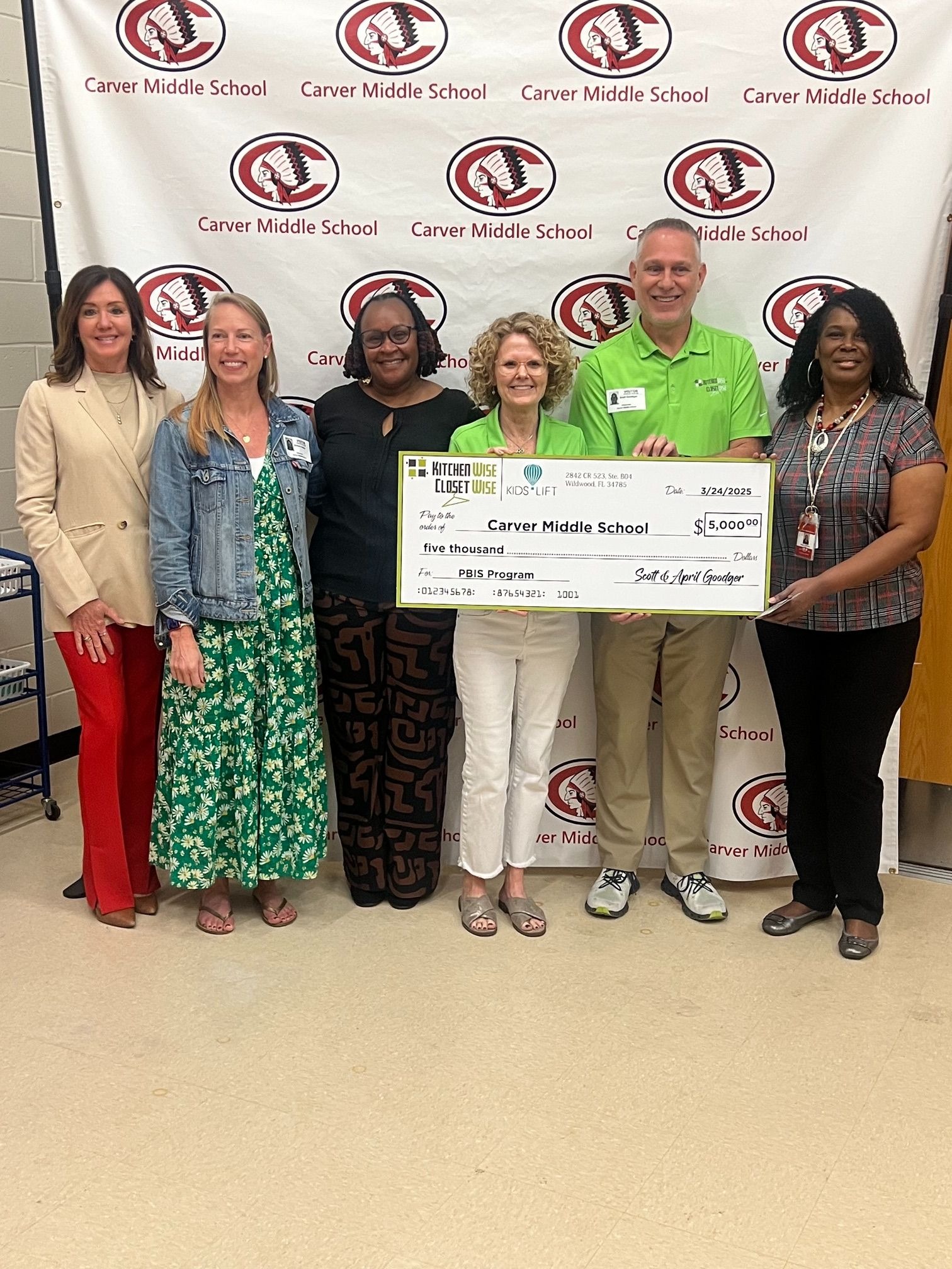 The team holding a check to donate to the middle school
